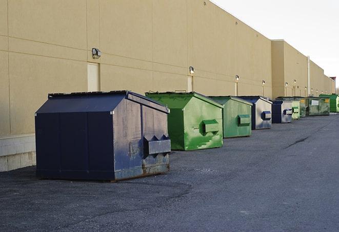 a construction worker unloading debris into a blue dumpster in Clearfield